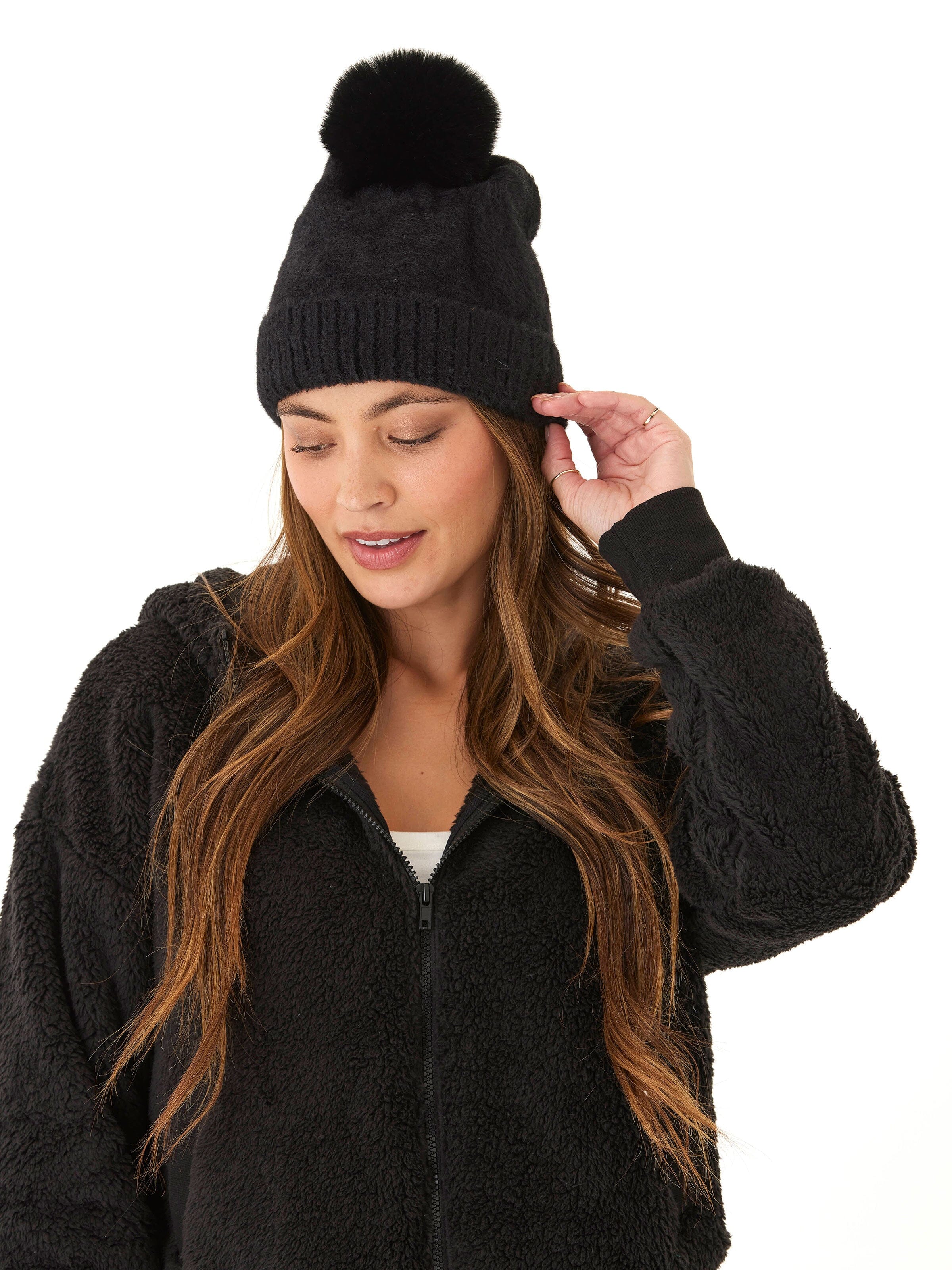 A stylish black fuzzy knit beanie with a pom-pom detail on top