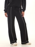 Women's black boot cut lounge pants with stark white contrast piping and a relaxed, flared fit.