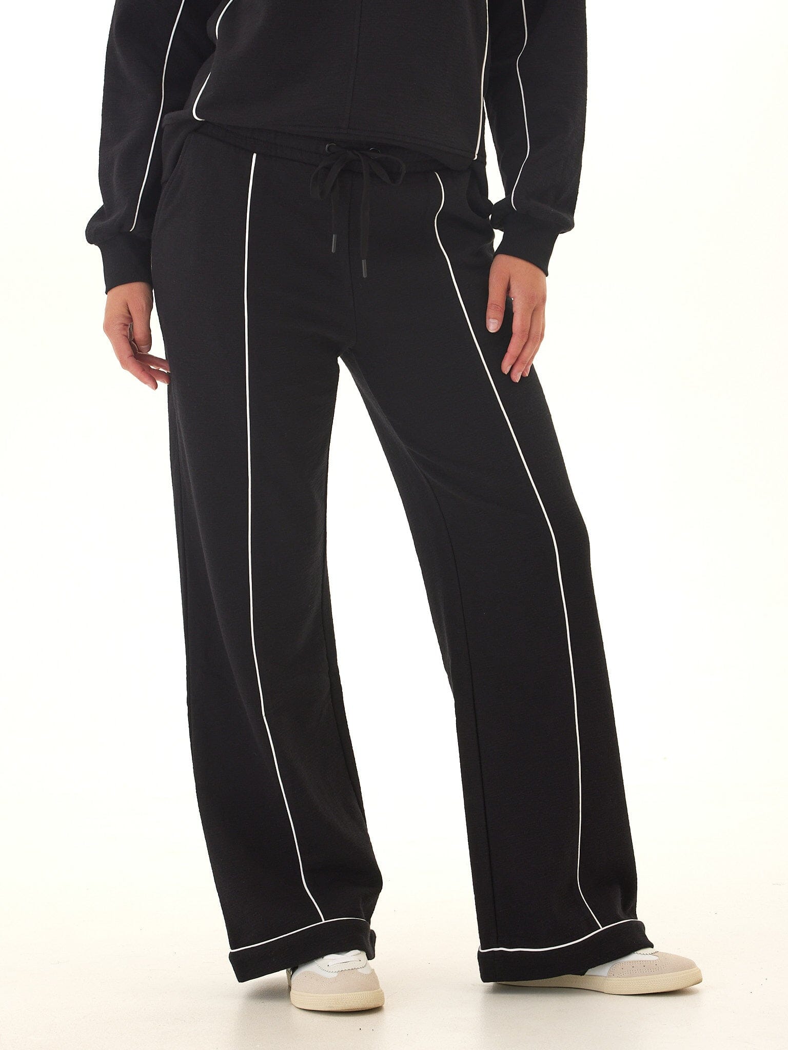 Women's black boot cut lounge pants with stark white contrast piping and a relaxed, flared fit.
