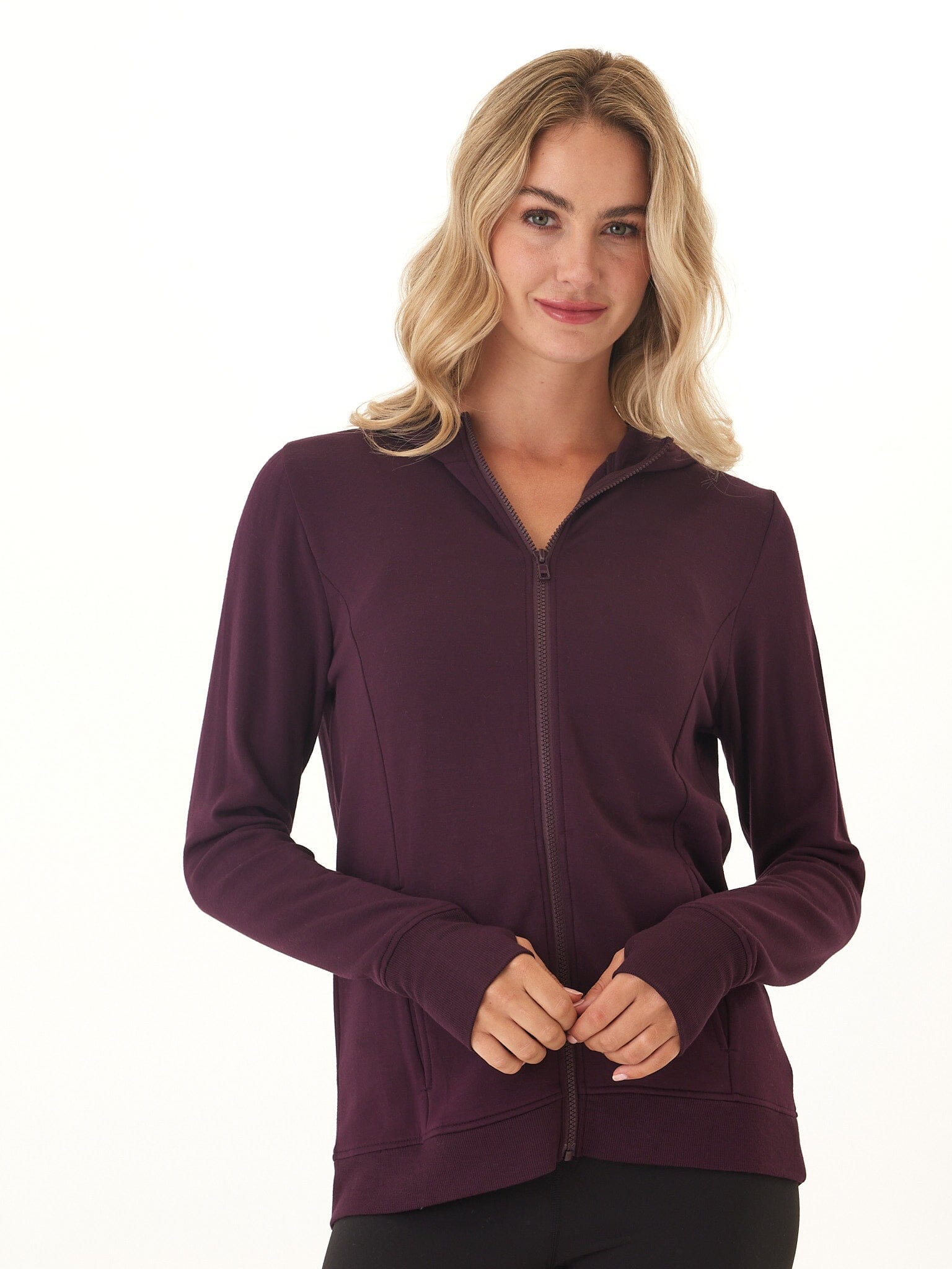 Woman wearing a soft Neyra Feather Fleece full-zip hoodie with front pockets and thumbhole sleeves.