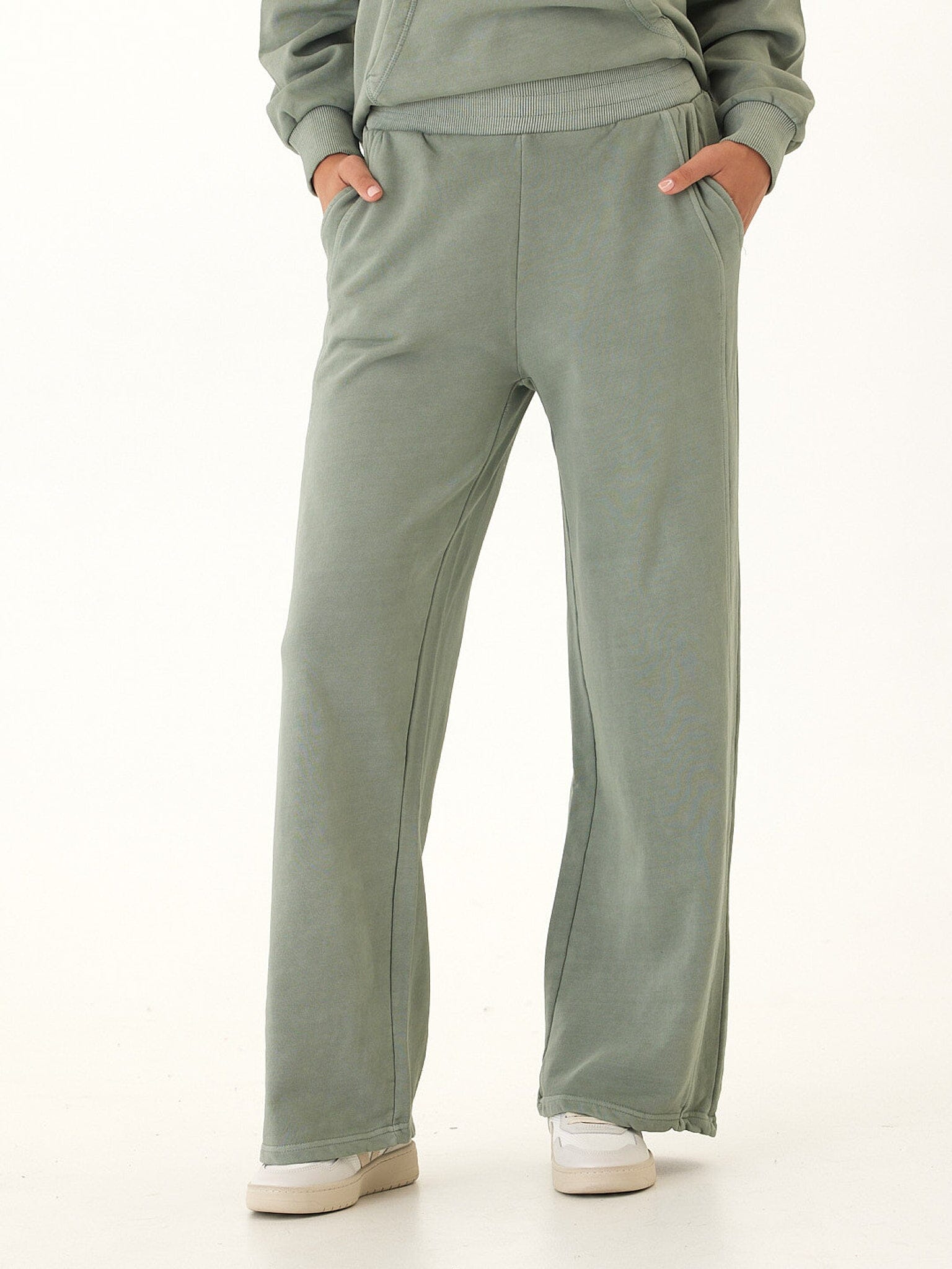 Woman wearing minimalist sage green Feather Fleece sweatpants with a soft, fluid drape.