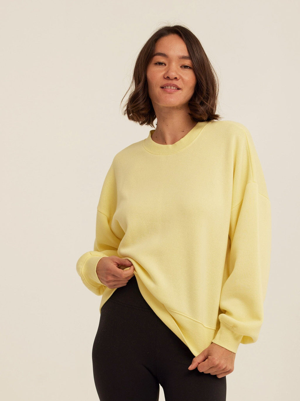 Women wearing a yellow solid color relaxed fit Triblend Fleece sweatshirt