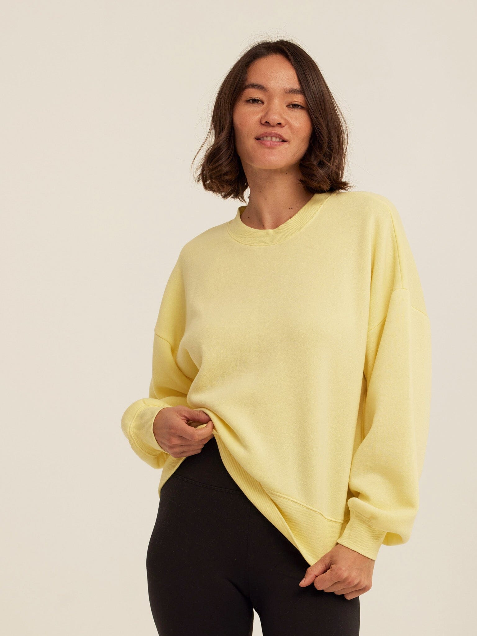 Women wearing a yellow solid color relaxed fit Triblend Fleece sweatshirt