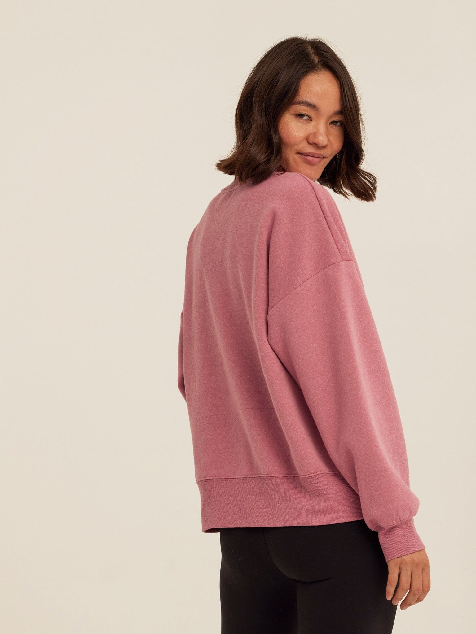 Woman wearing a dusty-rose core triblend fleece crewneck sweatshirt
