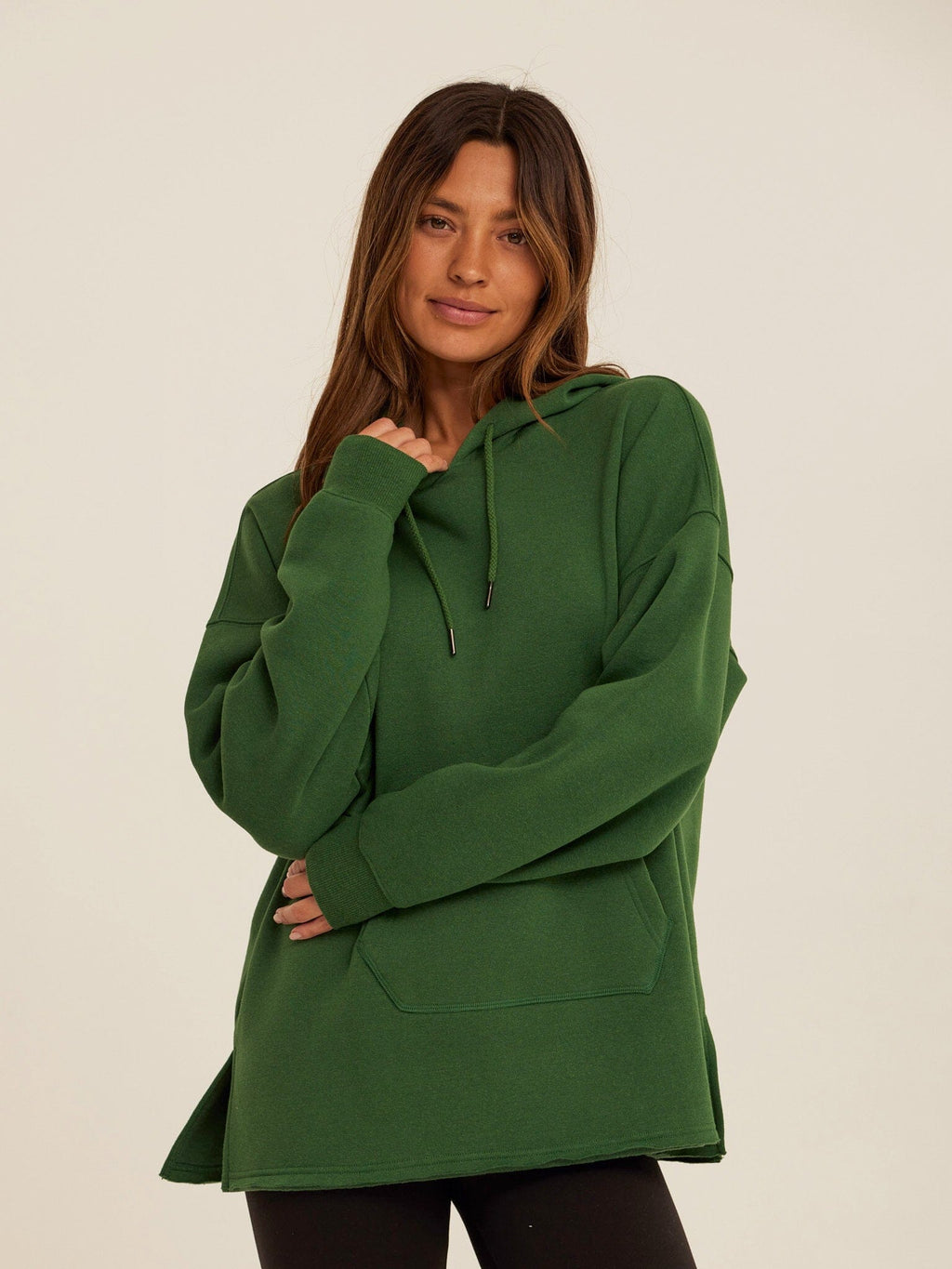 Woman wearing a relaxed-fit deep forest green triblend fleece pullover hoodie with a kangaroo pocket.