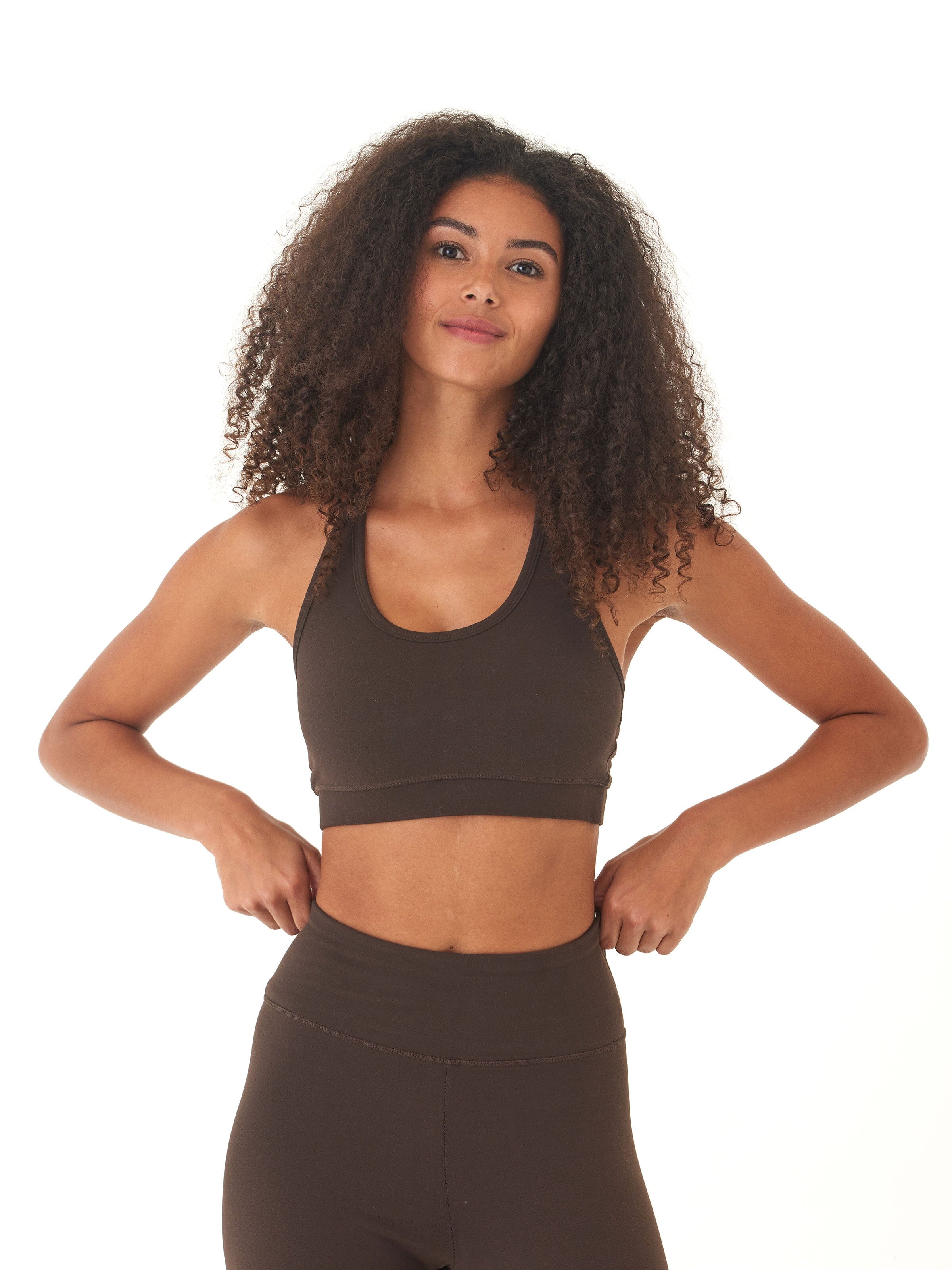 Dark brown women's sports bra featuring a scoop neckline and strappy back design against a neutral background.