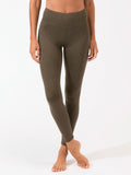 Woman wearing olive green high-rise ankle length leggings in a minimalist sporty style.