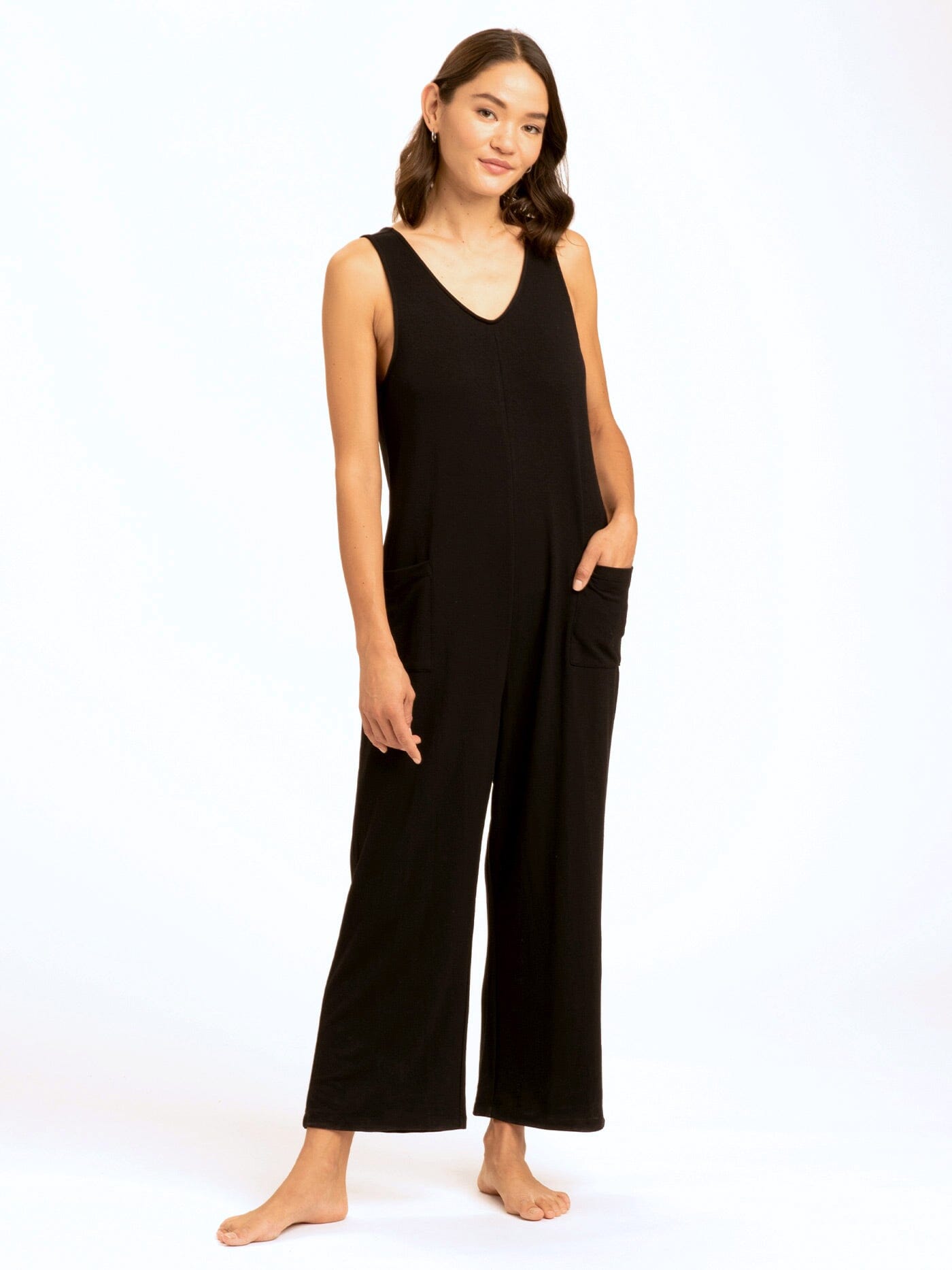 Woman wearing a relaxed-fit, sleeveless black wide-leg jumpsuit with patch pockets