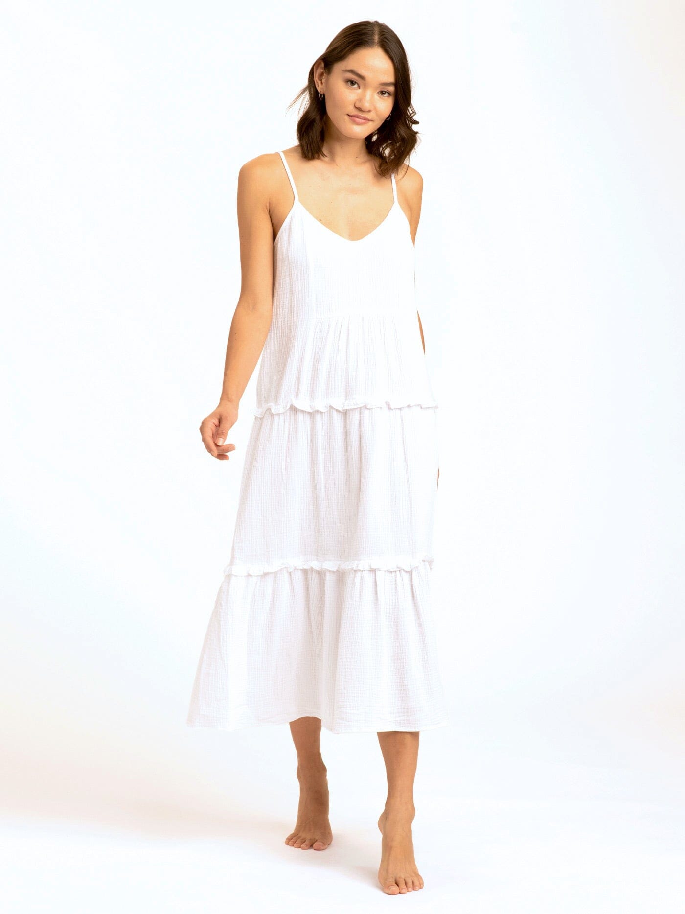 Model wearing a white sleeveless Gina Gauze Ruffle Tiered midi dress in a bohemian, beach-wear setting.