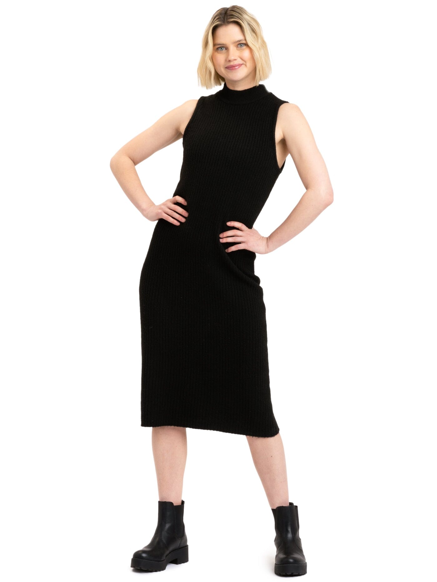 A woman wearing a sleeveless, black rib knit turtleneck midi dress in a fitted silhouette.