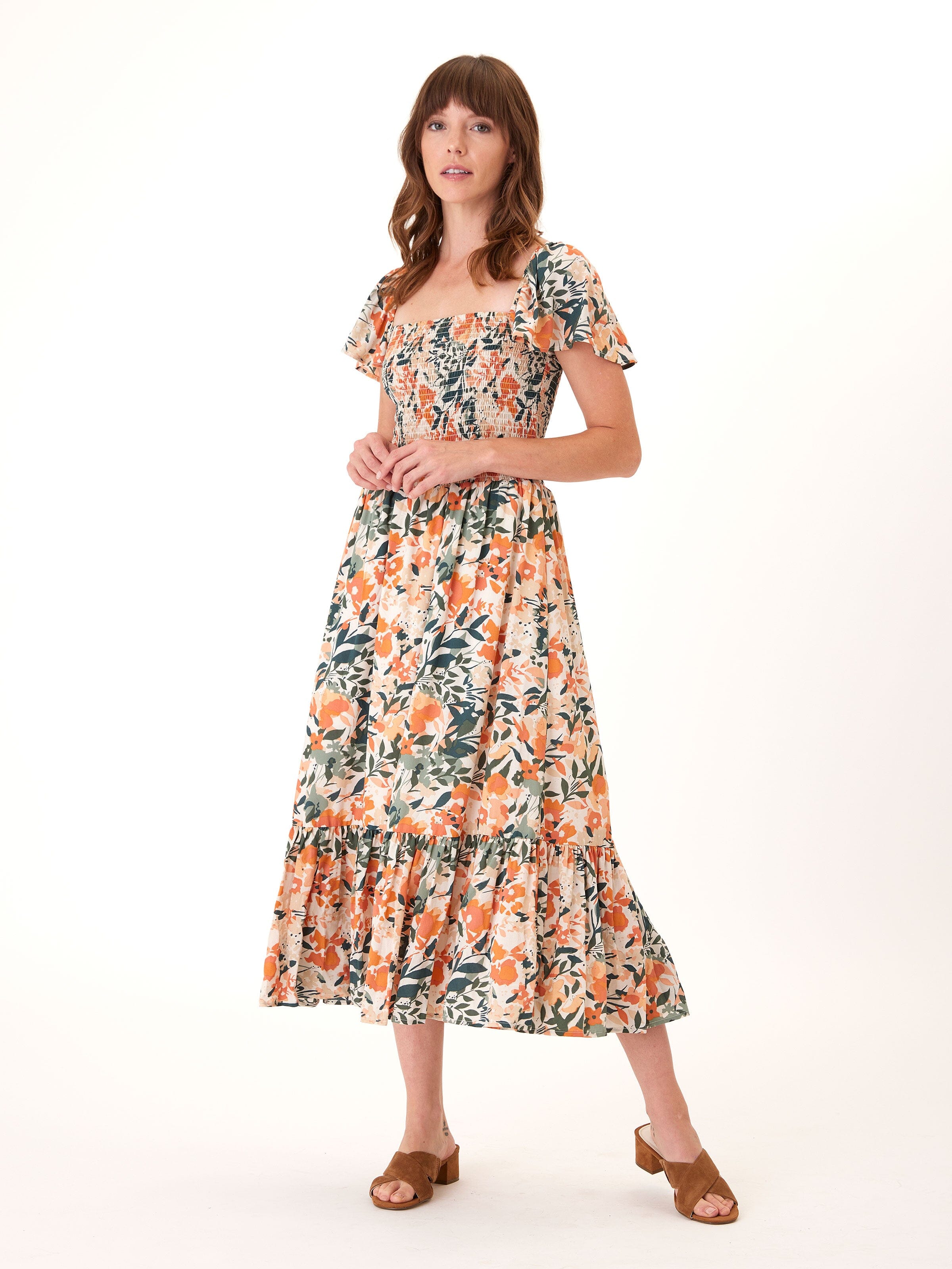 A flowy midi dress in a floral print with orange, forest-green, and cream colors, featuring an elasticized bodice.