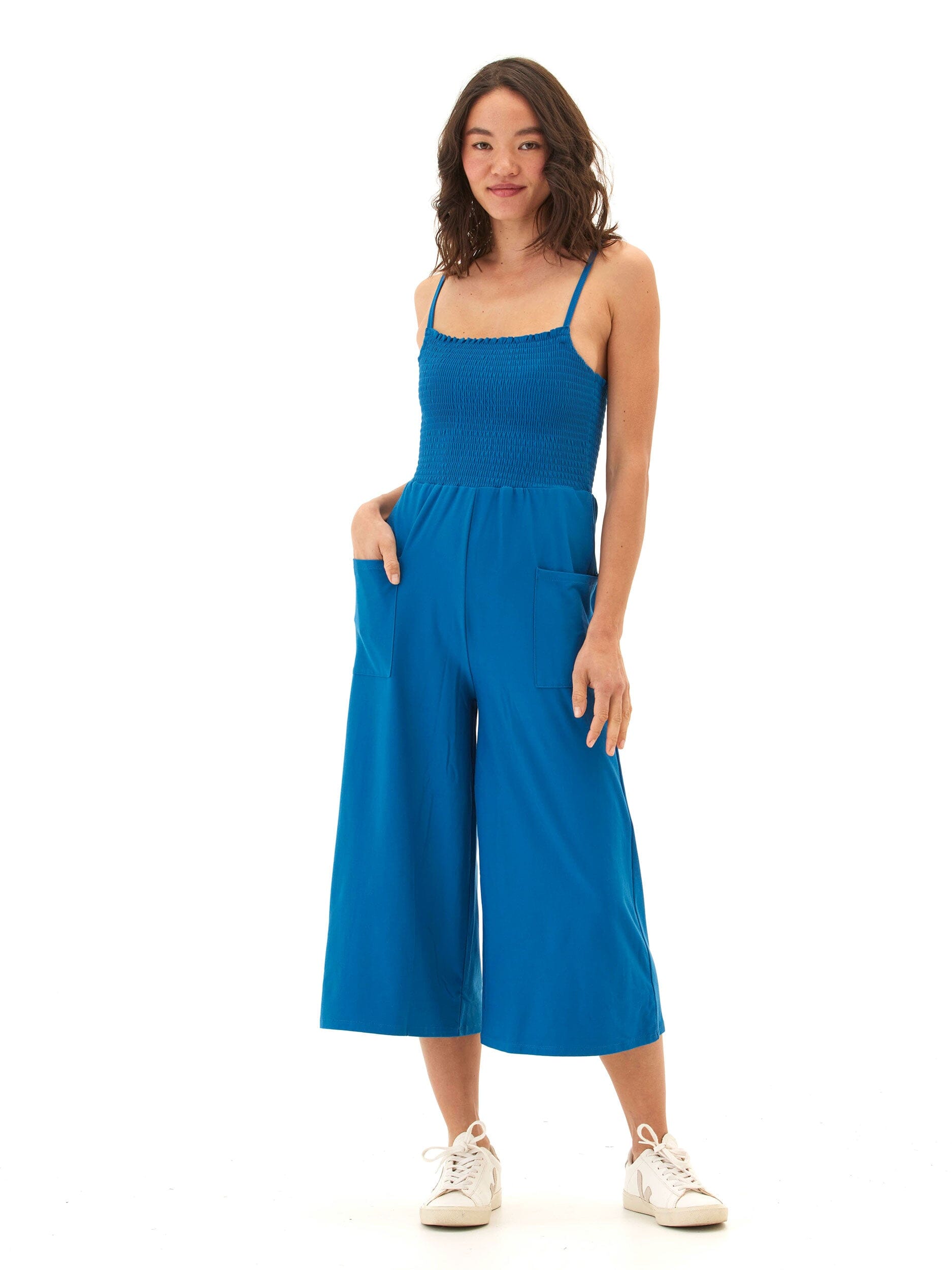 Woman wearing a sleeveless, wide-leg royal blue knit jumpsuit with a square neckline
