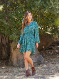 Model wearing a flowy teal, white, and peach vintage floral print button-front smocked dress
