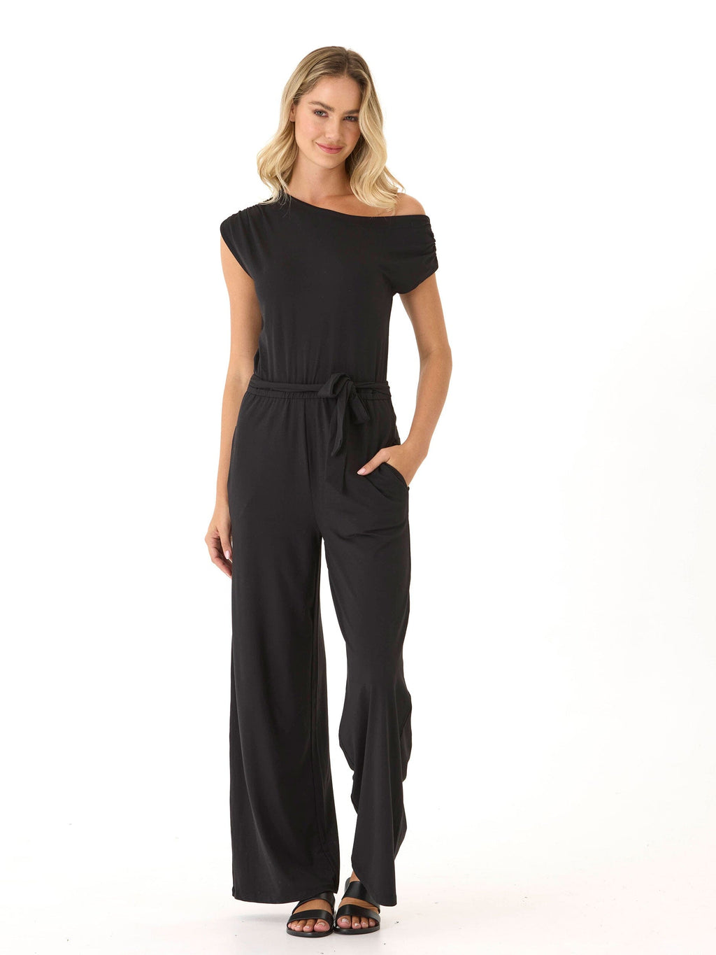Model wearing a black off-the-shoulder wide-leg knit jumpsuit with a relaxed silhouette and side pockets