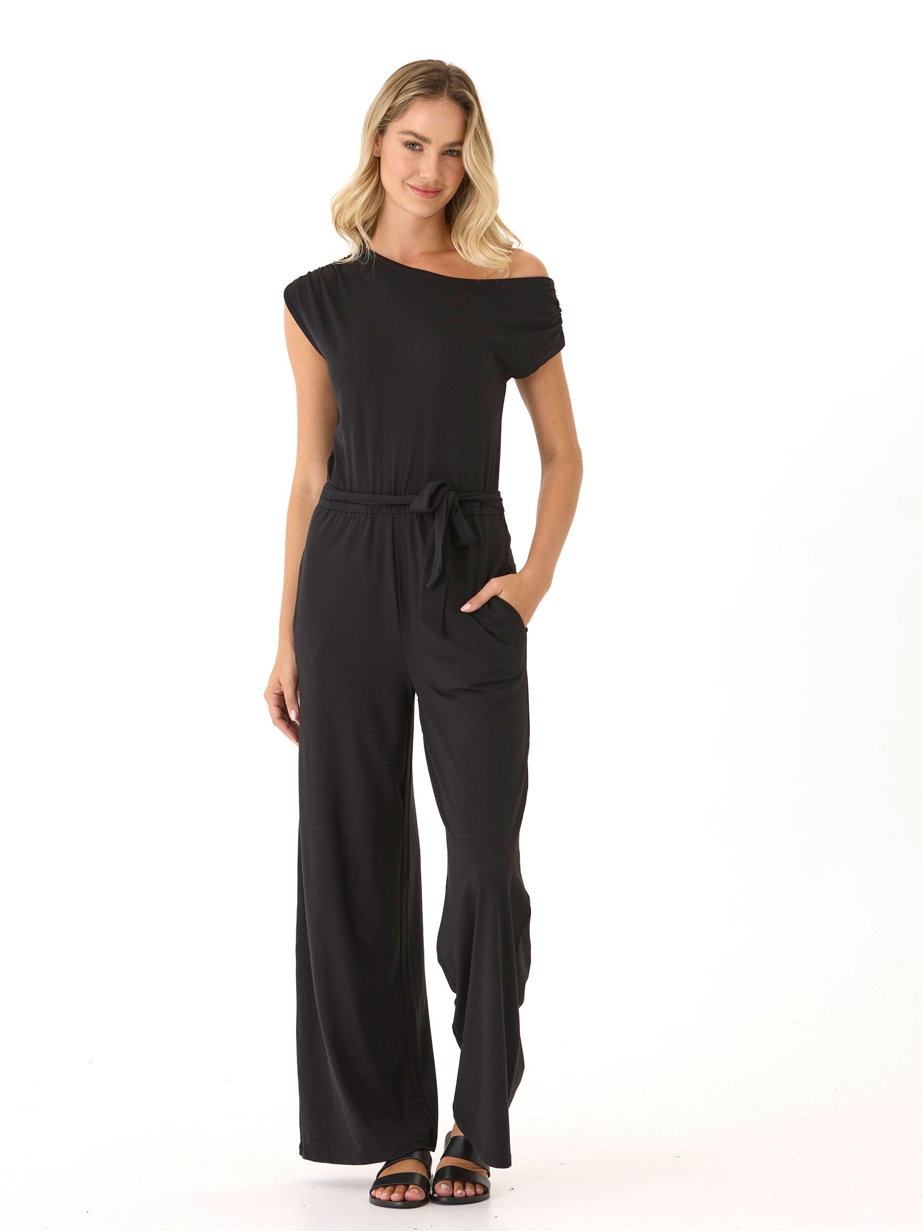 Model wearing a black off-the-shoulder wide-leg knit jumpsuit with a relaxed silhouette and side pockets