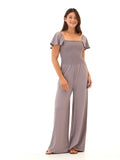 A woman wearing a dusty purple, wide-leg Luxe Jersey jumpsuit with a square neckline and flutter sleeves.