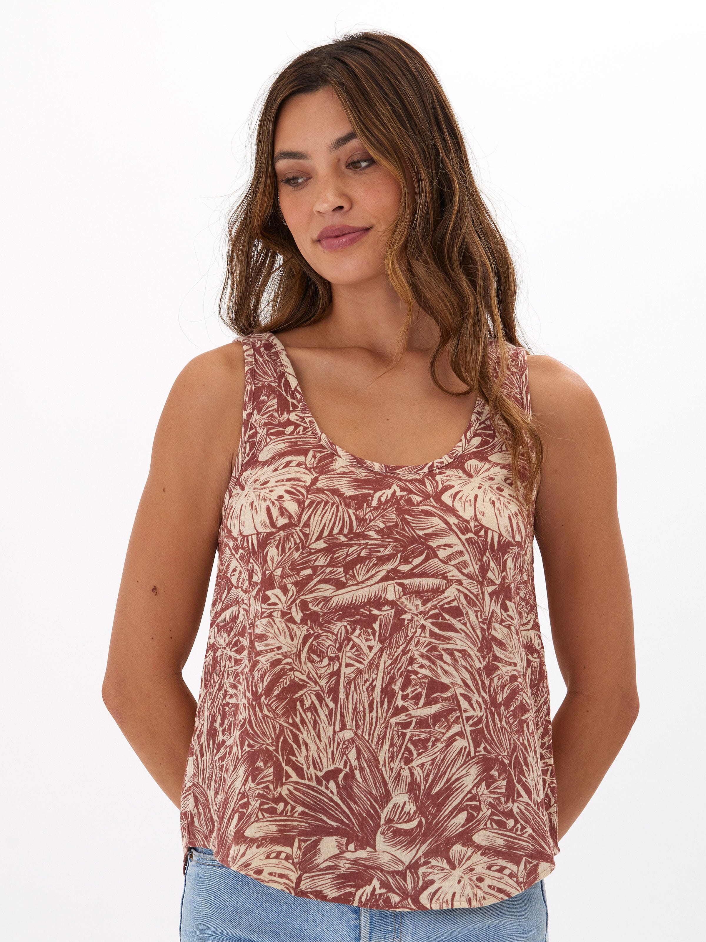 Woman wearing a flowy rust-colored Syrena organic cotton gauze tank with scoop neck design.