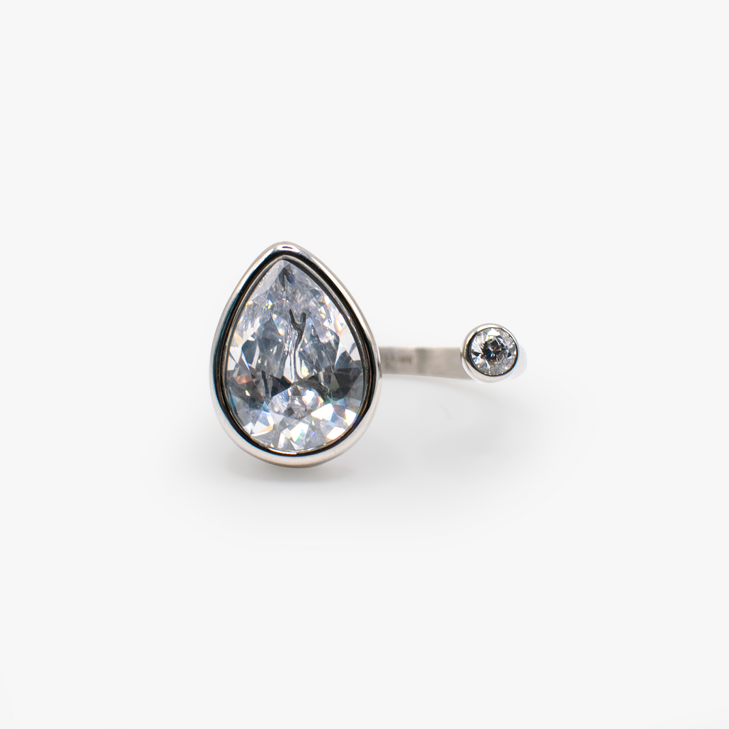 A polished silver-tone ring featuring a statement-sized pear-cut clear crystal stone in a bezel setting.