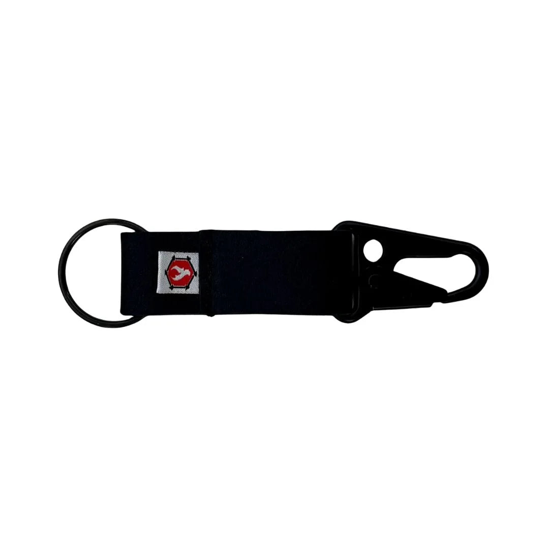 Monochromatic black leather keychain clip featuring a small red icon logo, industrial minimalist design.