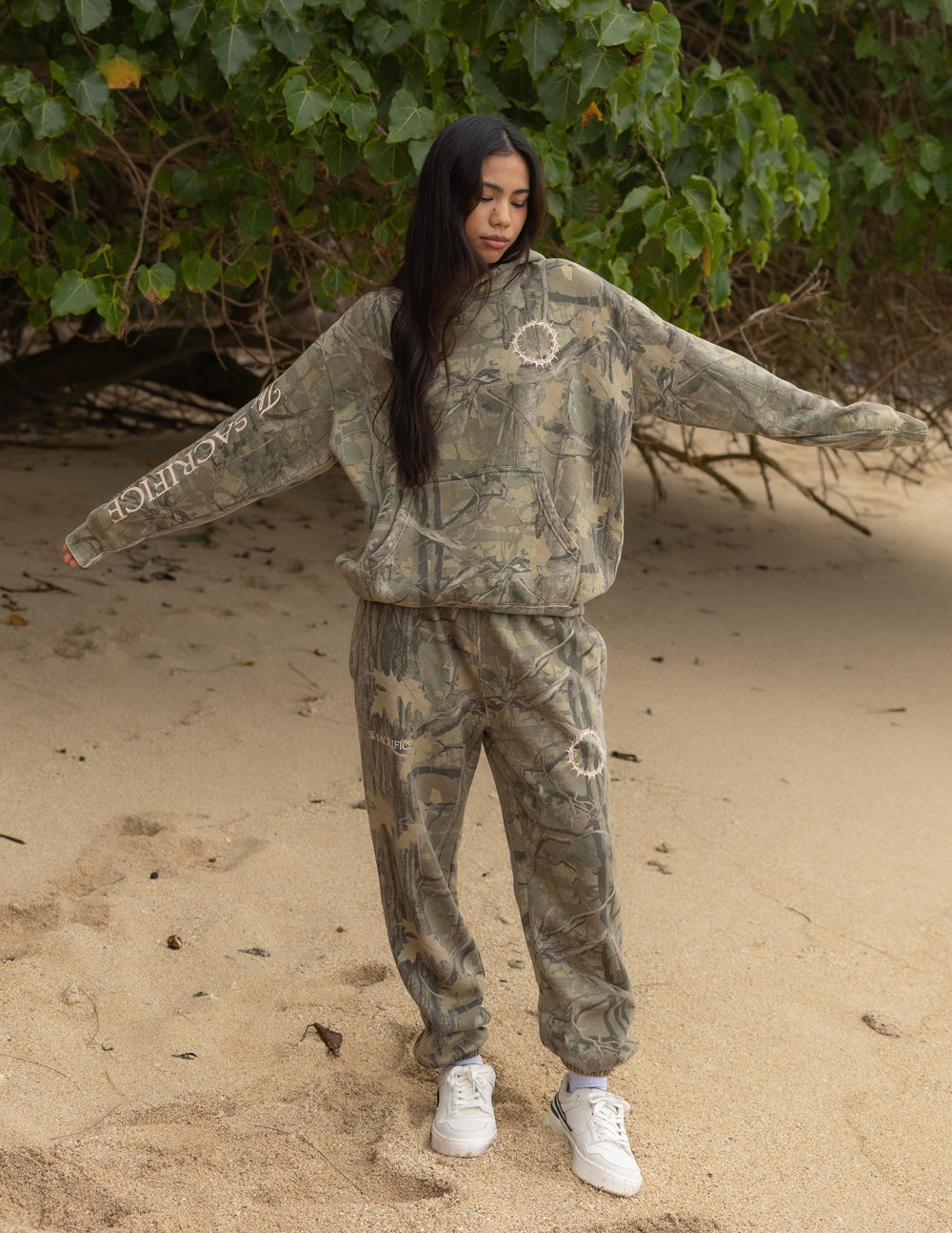 The Sacrifice unisex camo hoodie featuring green, brown, and tan camouflage print for a streetwear aesthetic.