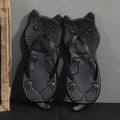 A pair of black and a pair of gold cat-shaped flip flops displayed against a dark background.