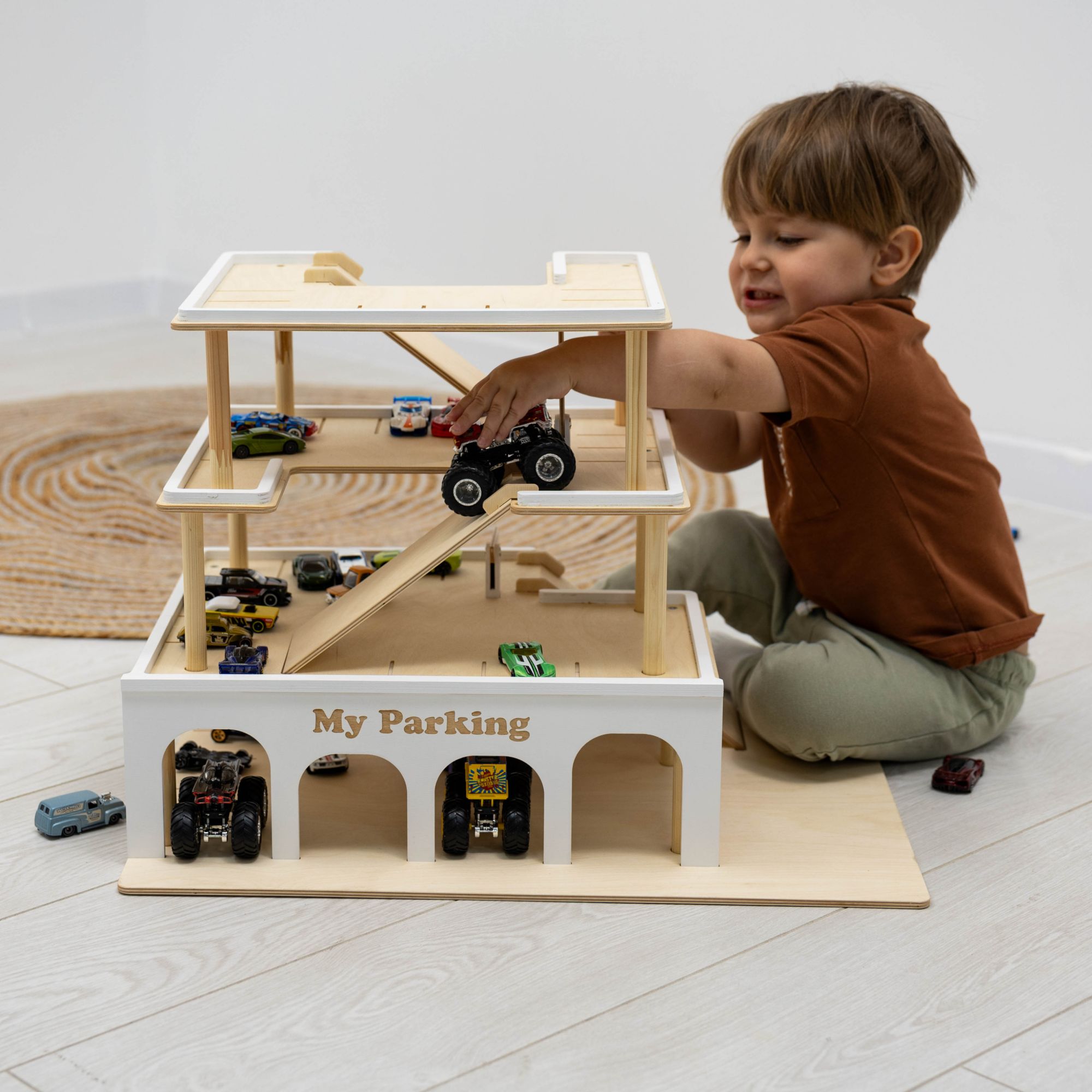 Minimalist wooden toy parking garage with elevator in a neutral, modern nursery setting.