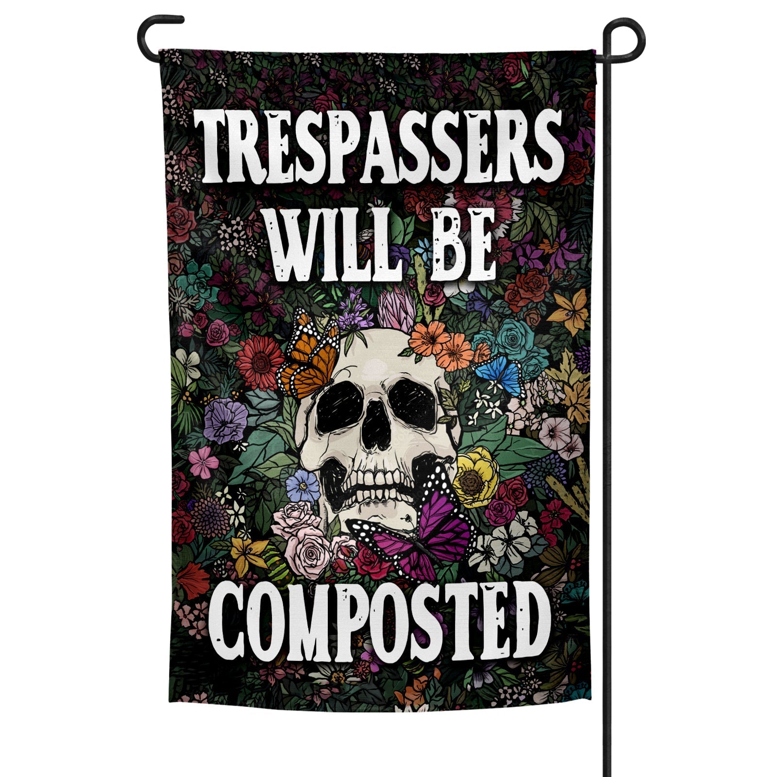 Trespassers Will Be Composted garden flag in black and multi-color displayed on a metal stake in a garden setting.