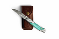Turquoise Crest Damascus steel folding knife with patterned blade on display