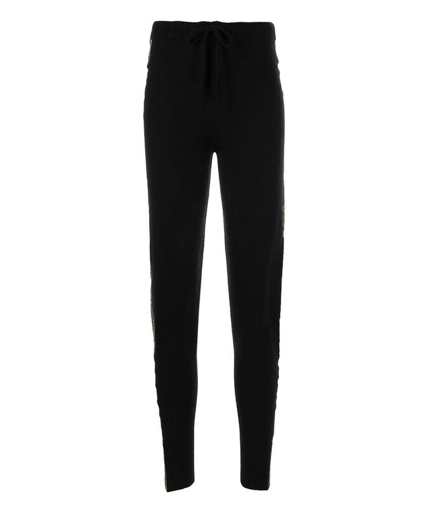 A pair of black cashmere jogger pants with a vertical metallic gold stripe down the side, shown on a model.
