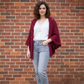 A close-up of a maroon and burgundy granny square crochet cardigan with three-quarter sleeves in a boho style.