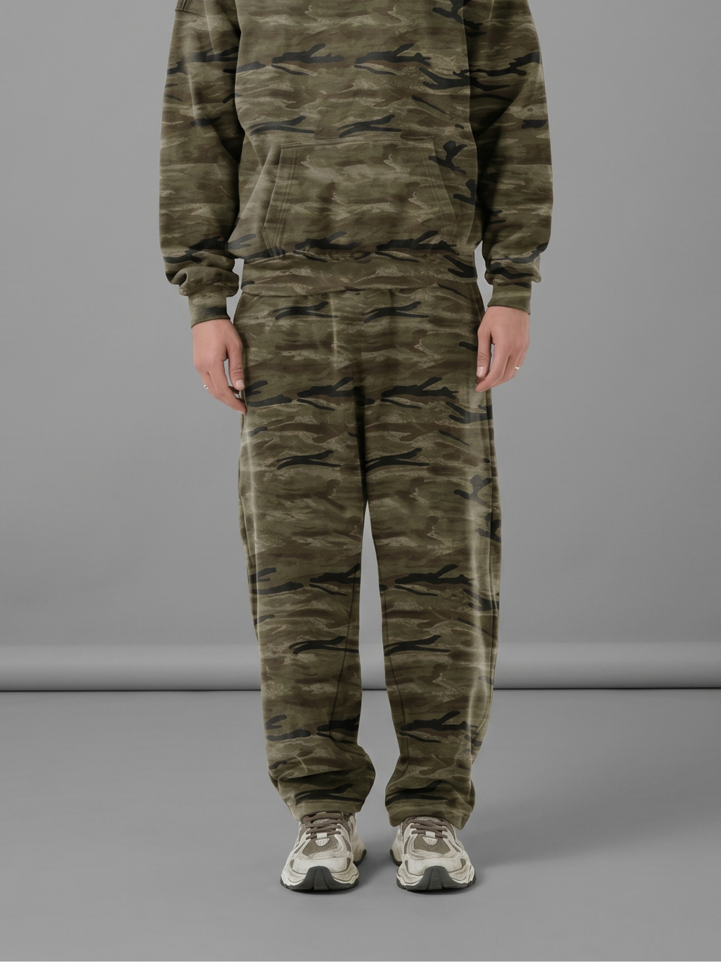 Unisex oversized heavyweight camo sweatpants in olive green and dark brown with a curved-leg silhouette.