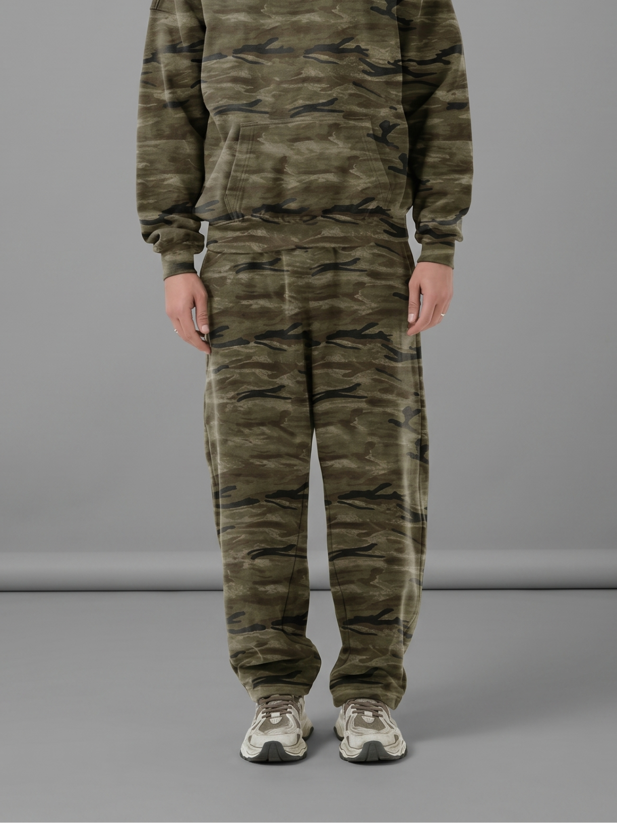 Unisex oversized heavyweight camo sweatpants in olive green and dark brown with a curved-leg silhouette.