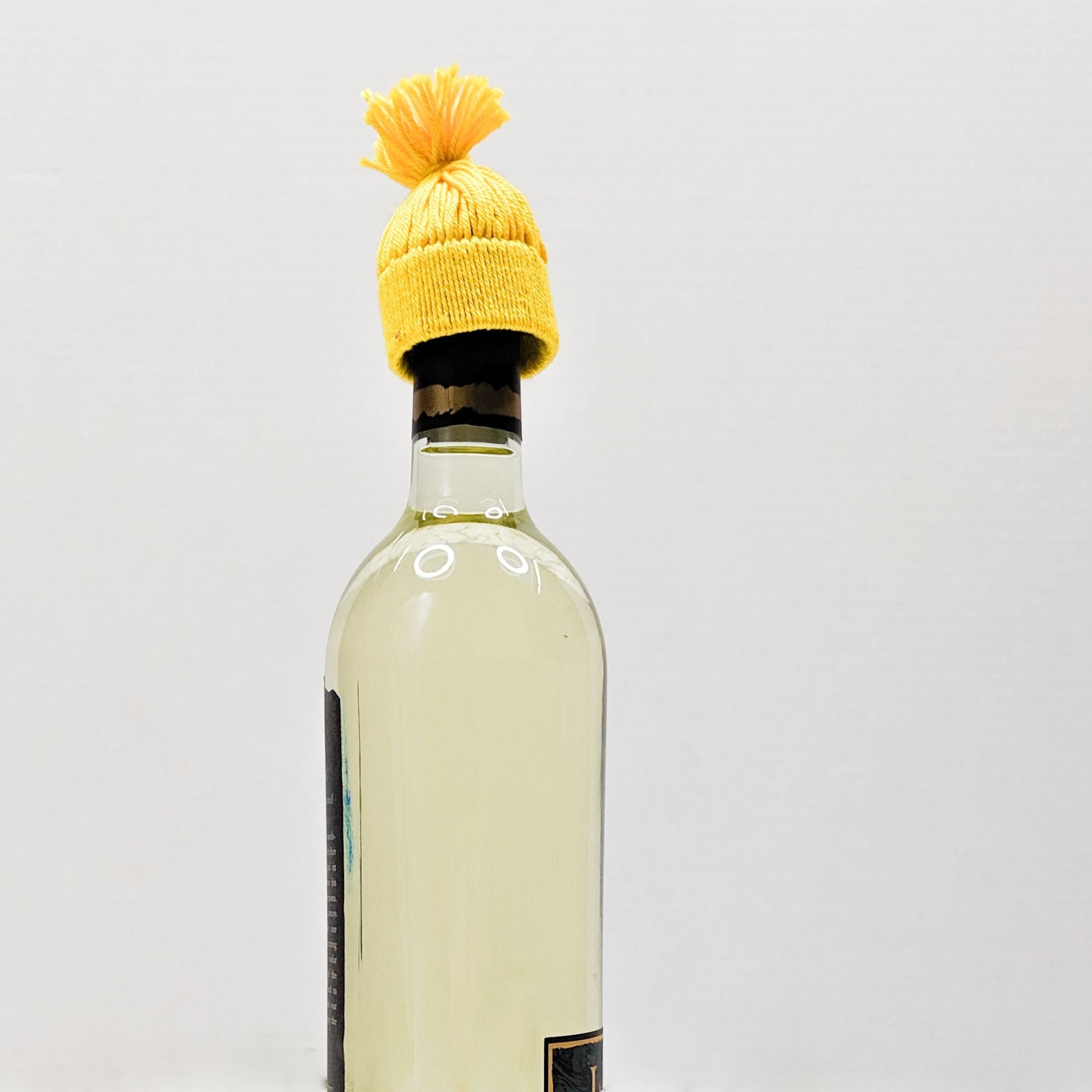 A vibrant yellow no-knit winter bottle hat used as a festive Christmas tabletop decoration.
