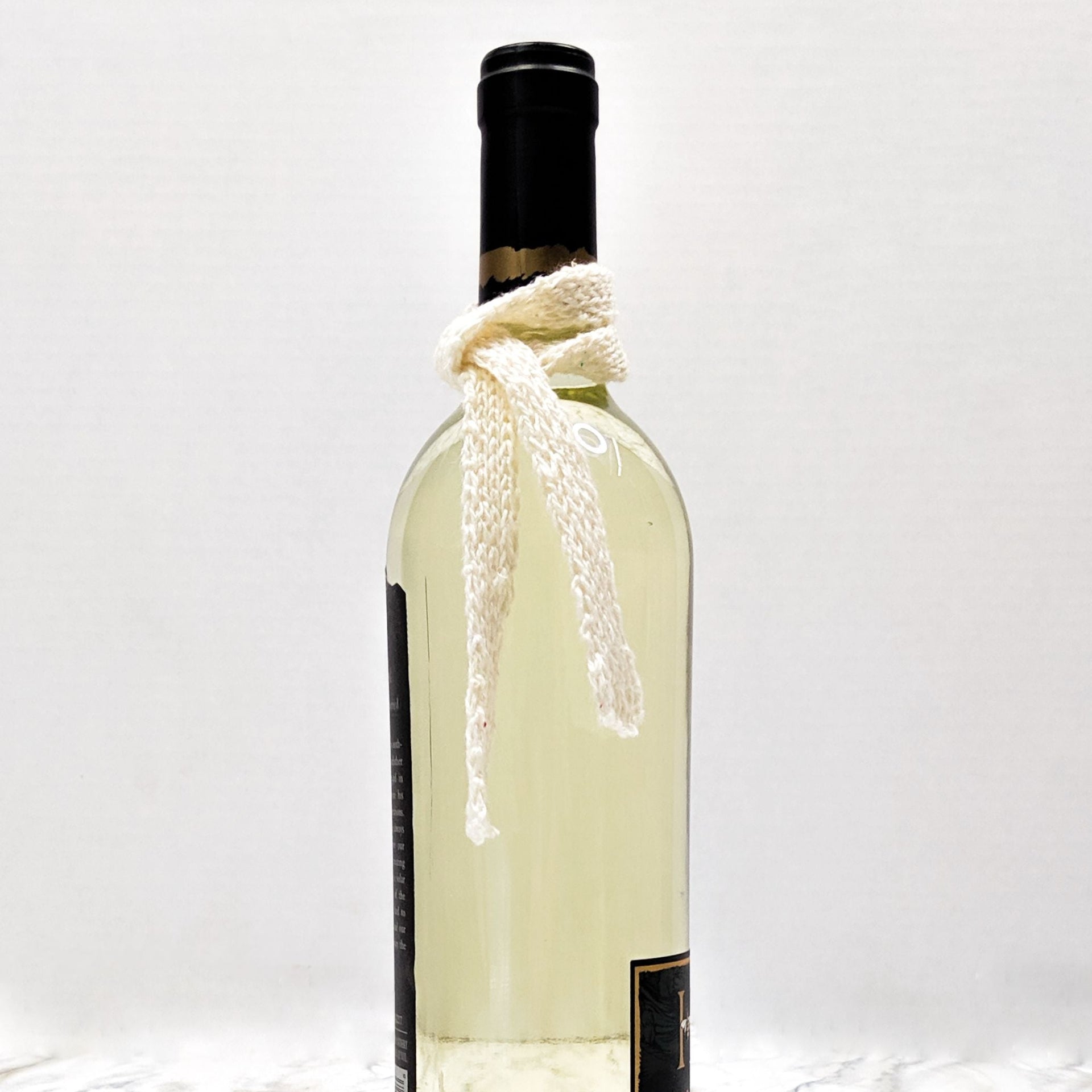 Miniature knitted scarf draped over a holiday wine bottle as seasonal home decor.
