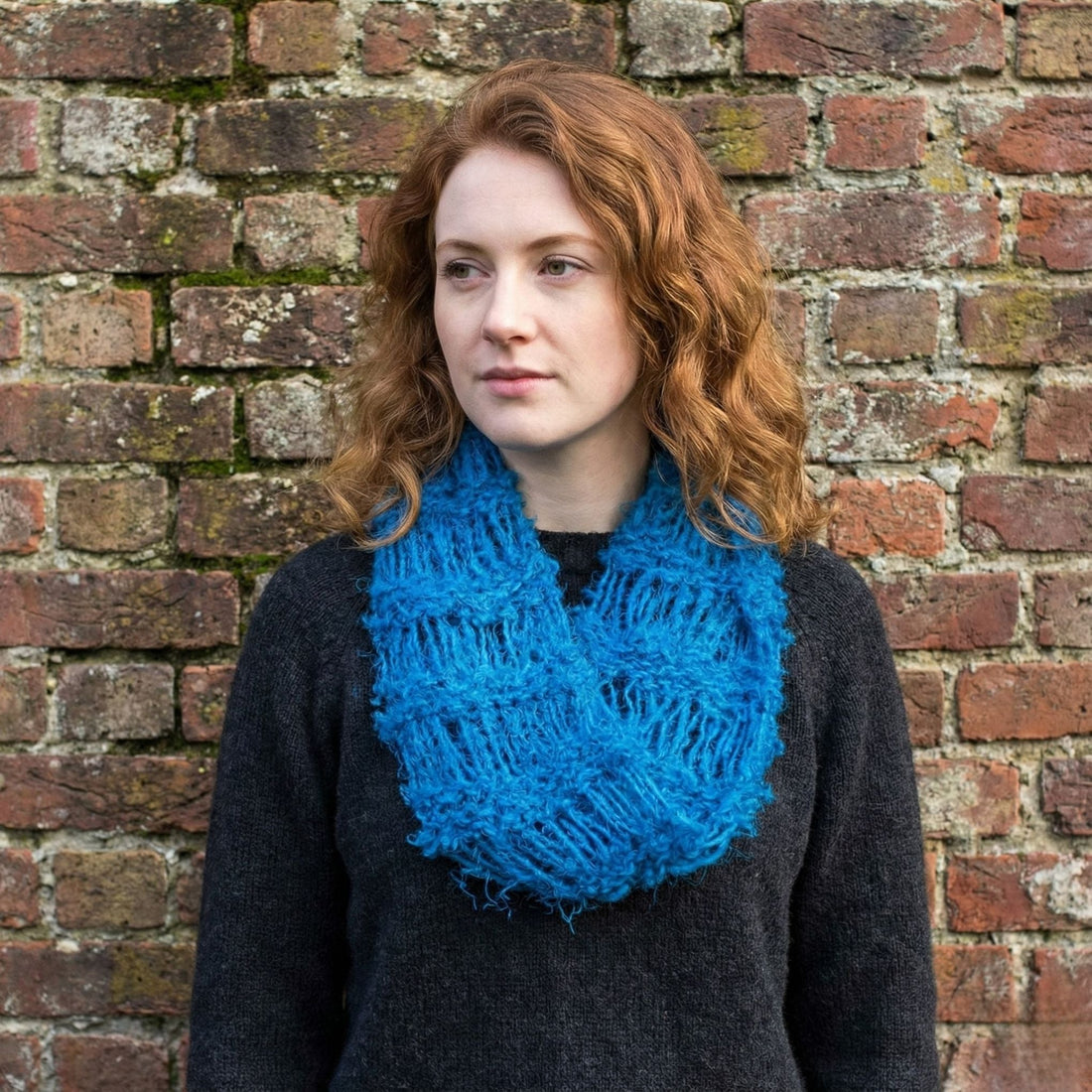 An elongated infinity scarf made from soft yarn, styled wrapped around a mannequin neck.