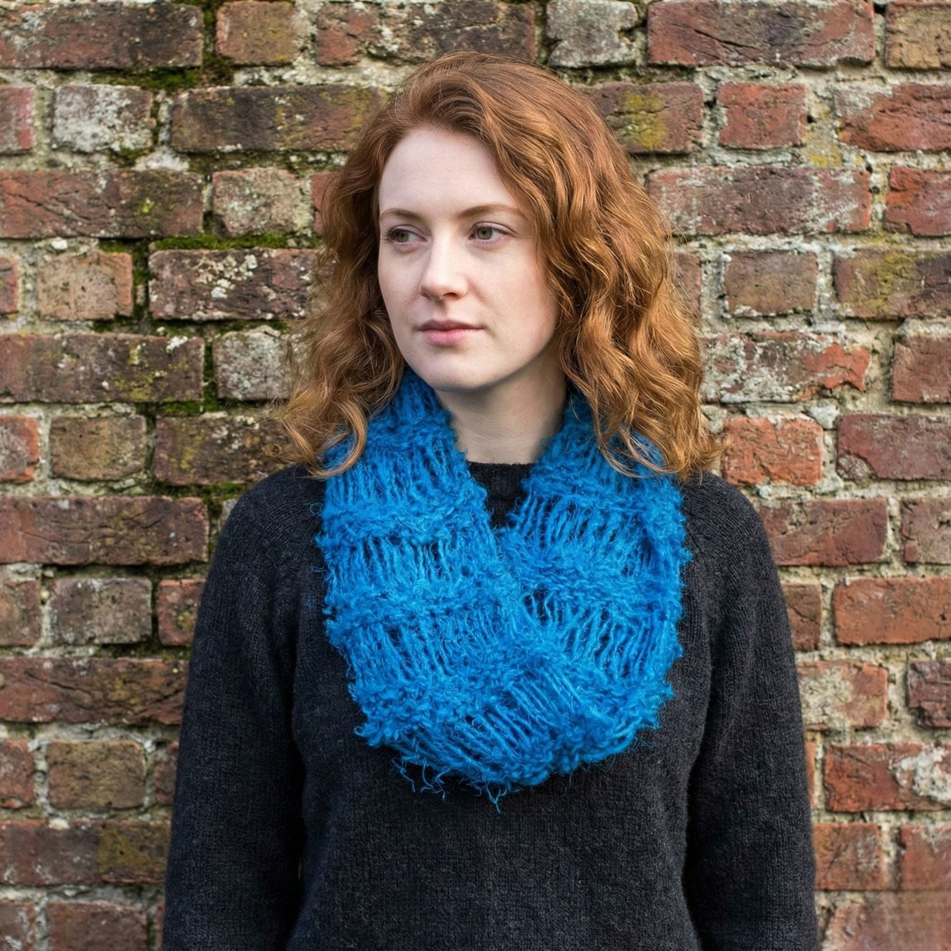 An elongated infinity scarf made from soft yarn, styled wrapped around a mannequin neck.