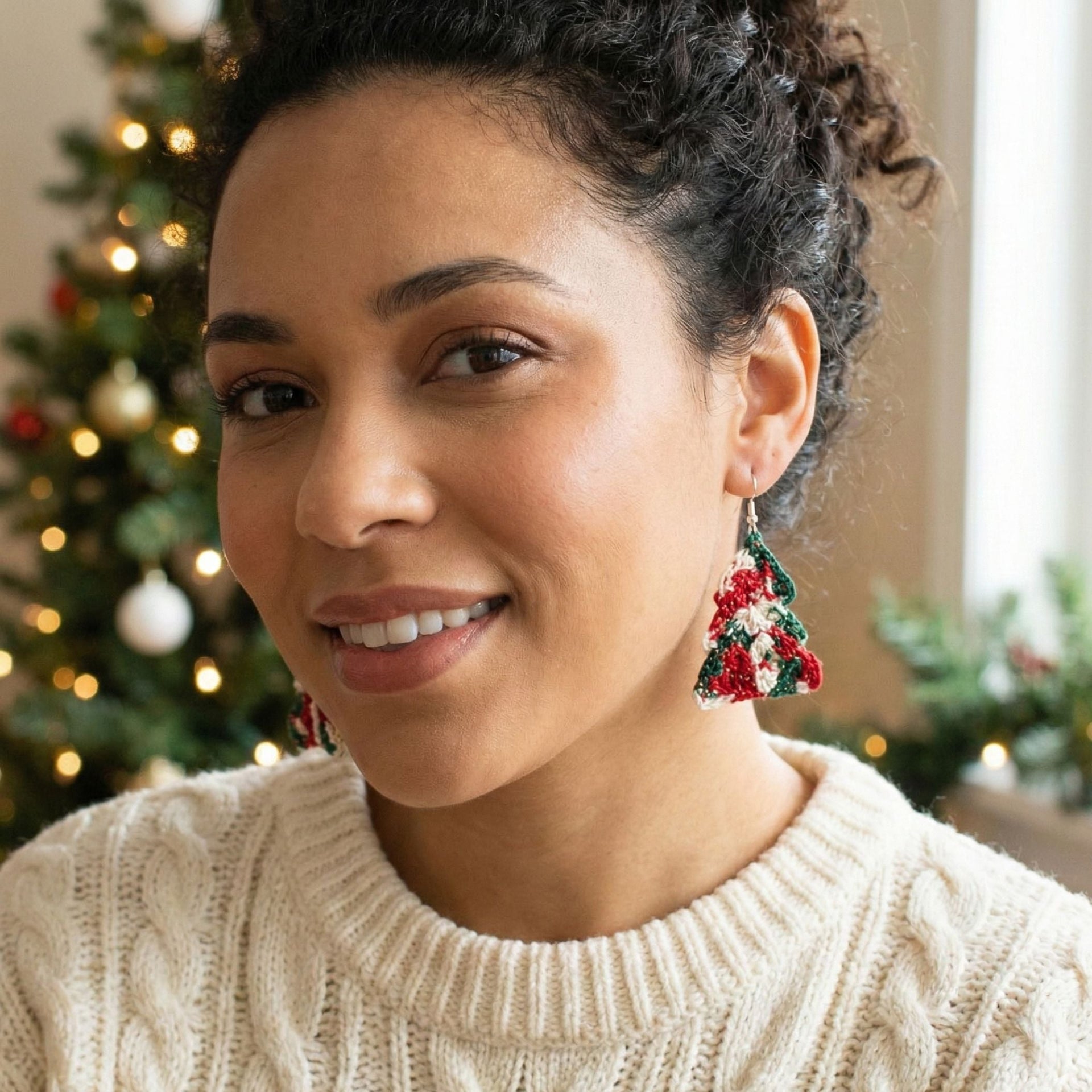 Close up of handmade crocheted Christmas tree earrings on a holiday background