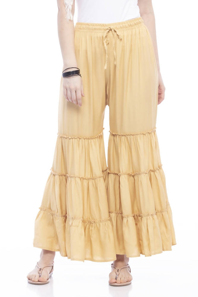 Woman wearing solid golden rayon cotton palazzo pants in a wide-leg silhouette.