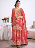 A woman wearing a vibrant red embroidered Chinon Silk Salwar Suit with a matching dupatta for a wedding celebration.