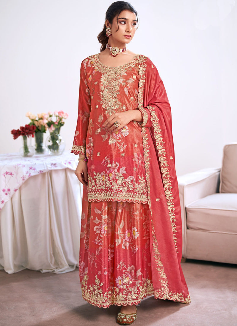 A woman wearing a vibrant red embroidered Chinon Silk Salwar Suit with a matching dupatta for a wedding celebration.