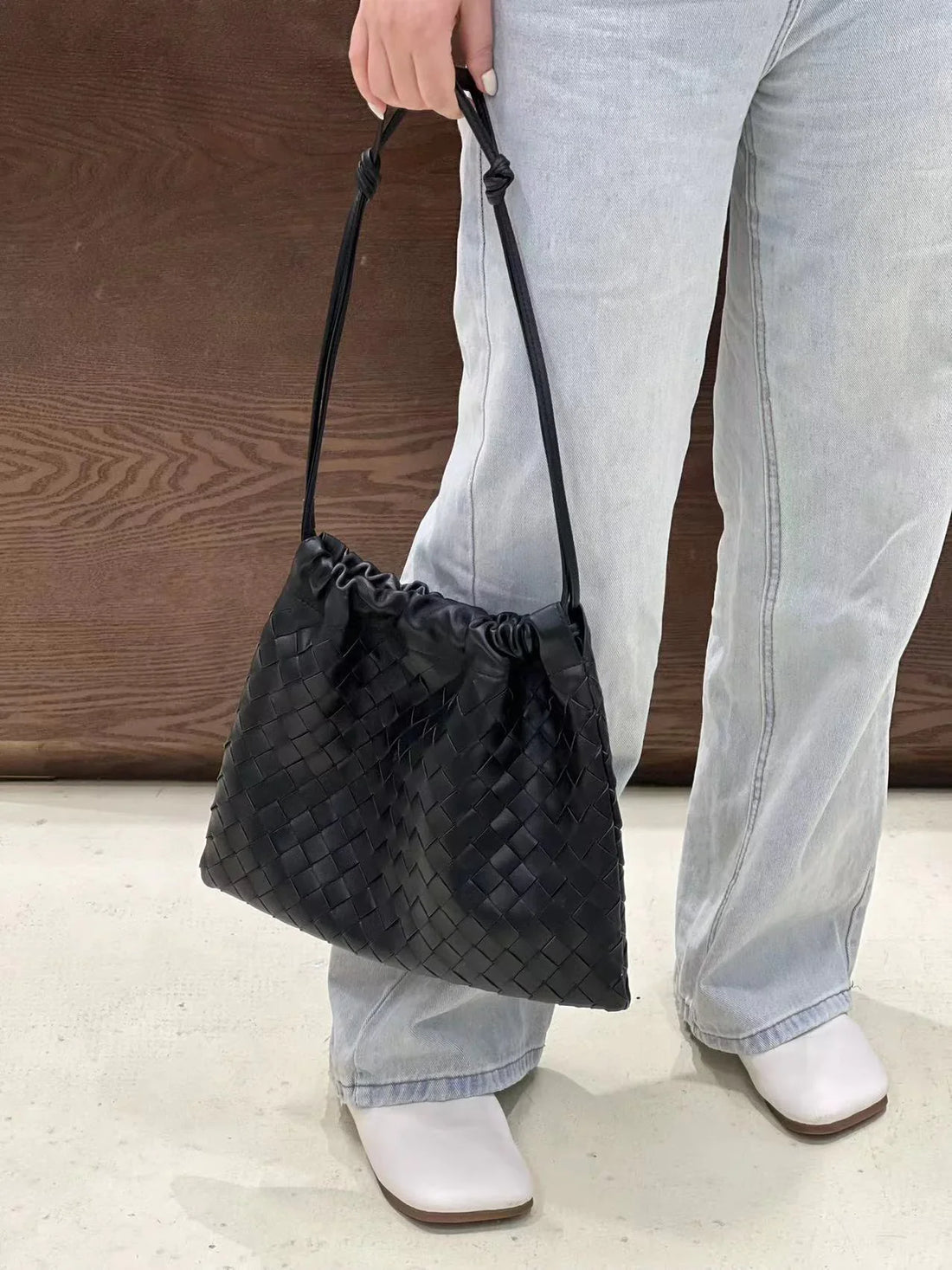 Woman wearing a black woven leather shoulder bag with a soft structure