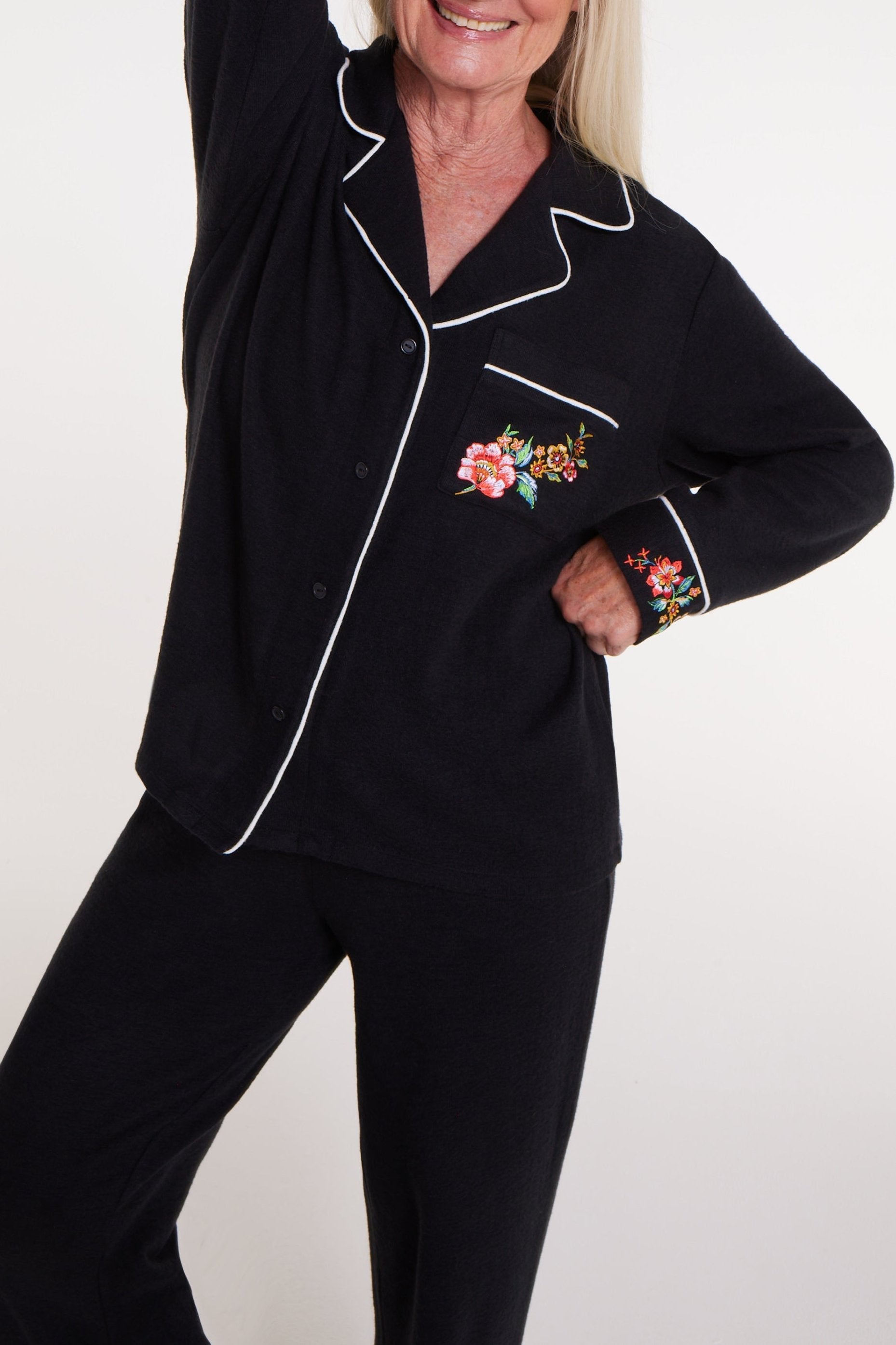Woman wearing black long sleeve pajama set with floral embroidery and magnetic closure detail