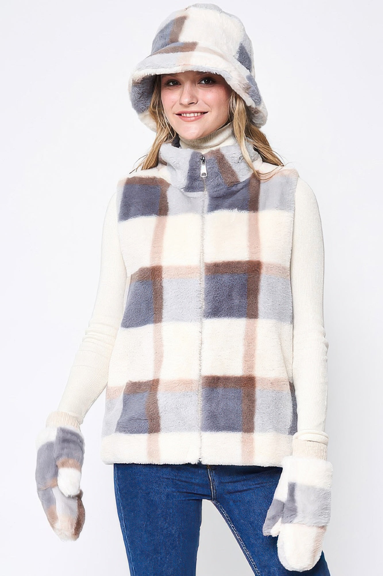 A woman wearing a plaid faux fur vest with a matching bucket hat and mittens against a white background.