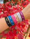 A stack of six colorful woven WWJD bracelets in the Cyber colorway displayed on a wrist