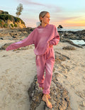 Model wearing vintage rose unisex jogger sweatpants with W.W.J.D logo on the leg at the beach.