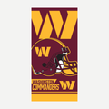Washington Commanders branded velour beach towel in burgundy and gold with a team helmet graphic