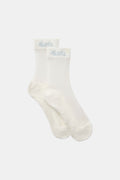 Close-up of a pair of off-white sheer golf socks with a cushioned footbed and Mantra script branding on the ribbed cuff.