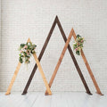 Modern wooden triangle wedding arch decorated for an outdoor ceremony
