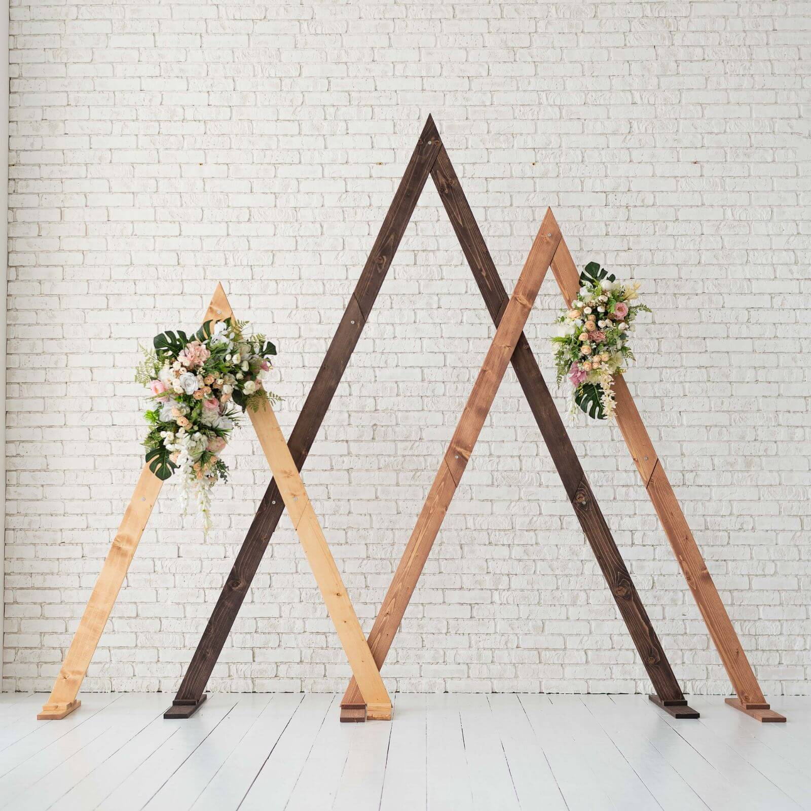 Modern wooden triangle wedding arch decorated for an outdoor ceremony