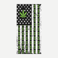 A rectangular beach towel featuring an American flag design with black and white stripes and a prominent green marijuana leaf pattern throughout.